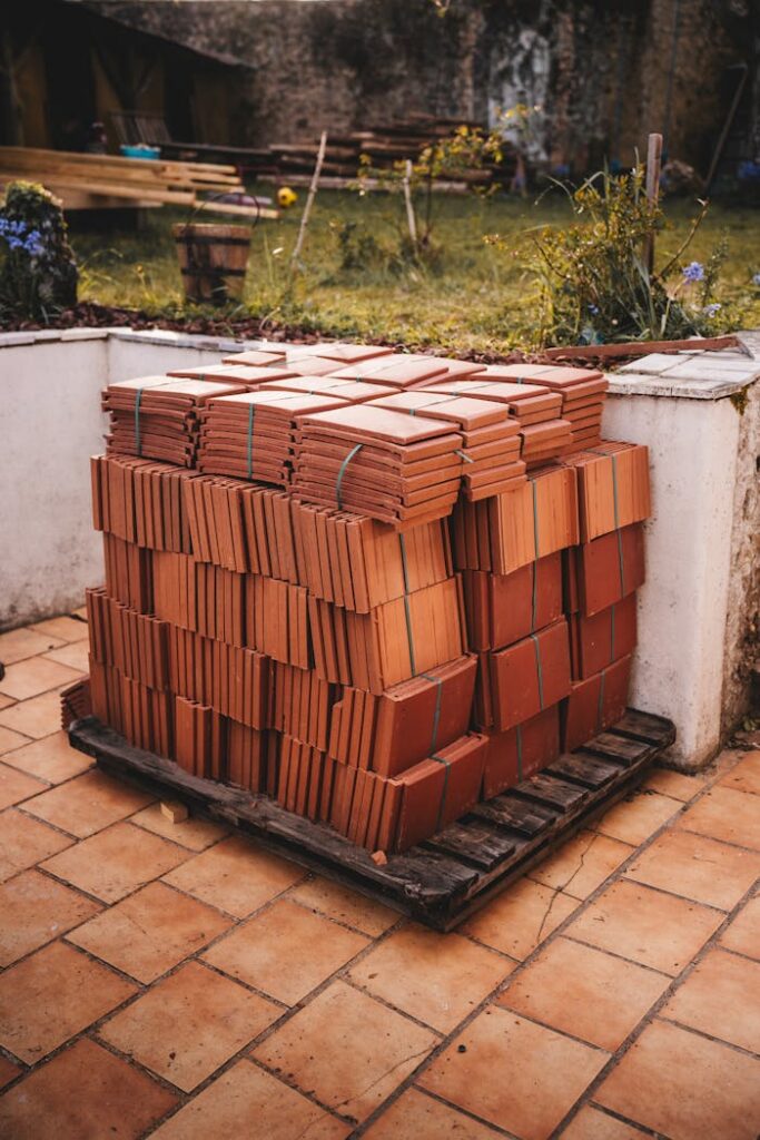 A pallet of stacked roof tiles placed on an outdoor patio area, ready for construction.
